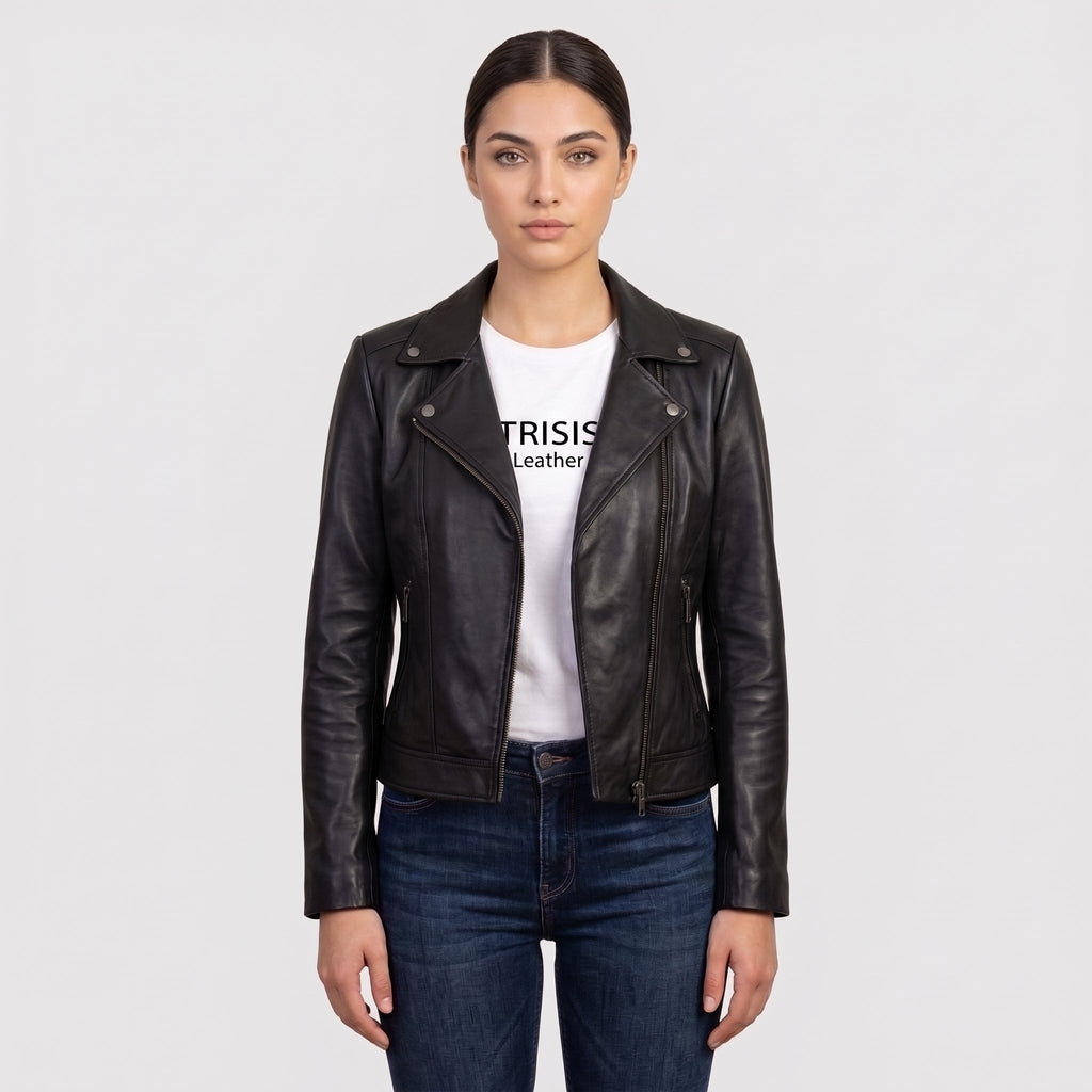 A woman modeling a black leather moto jacket over a white graphic t-shirt and dark blue jeans, shot against a solid light gray background.